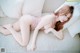 A woman laying on a couch in a pink lingerie.