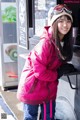 A woman in a pink jacket and hat standing in front of a food truck.