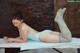 A woman in a blue bathing suit laying on a table.