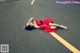 A woman in a red dress laying on the road.