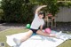 A woman sitting on a blanket with a ball in her hand.