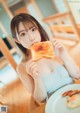 A woman sitting at a table eating a piece of toast.