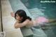 A woman in a pink bikini laying on the edge of a pool.