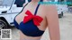 A woman in a blue bikini with a red bow on her chest.