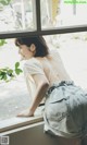 A woman leaning against a window looking out the window.