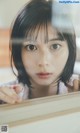 A woman looking out of a window with her hand on the window sill.