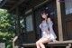 A woman sitting on a porch in front of a house.