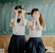 Two young girls in school uniforms covering their eyes with their hands.